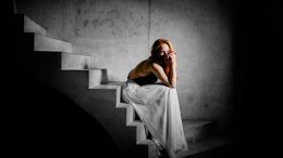 Kat Wulff sitzt im weißen Kleid auf einer Treppe