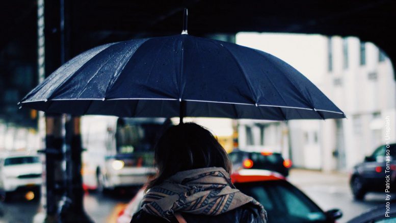 Frau mit Regenschirm unter einer Brücke