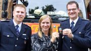 Zwei Feuerwehrmänner mit einer Frau präsentieren einen Charity Pin