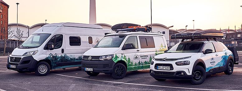 drei Camper und Wohnmobile auf einem Parkplatz