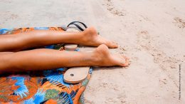 Beine einer Frau beim Sonnenbaden am Strand
