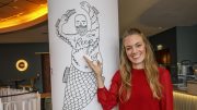Tessa Aust im neuen Reep Restaurant zeigt auf ein Raum-Tattoo