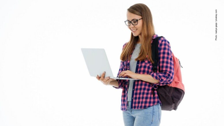 Studentin in karrierter Bluse stehend mit Laptop