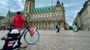 Ein First A Auslieferungsfahrer mit Fahrrad vor dem Hamburger Rathaus