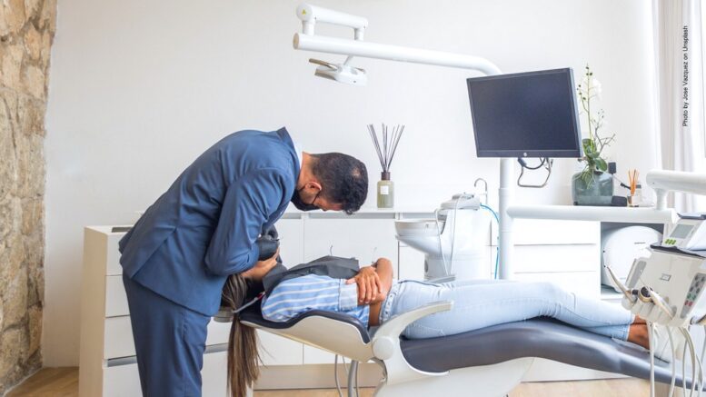 Blick auf einen Zahnarzt-Behandlungsstuhl mit Patientin. Zahnarzt in blauer Kleidung