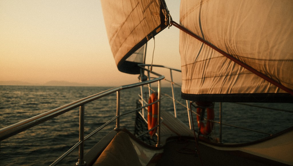 Sonnenuntergang auf einem Segelboot.  Blick Richtung Fock- und Hauptsegel