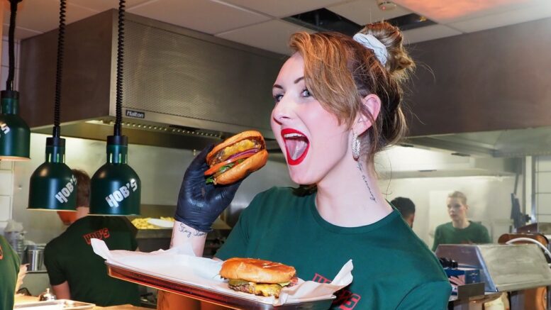 Ein HOB'S Burger Mitarbeiterin beißt in einen Burger