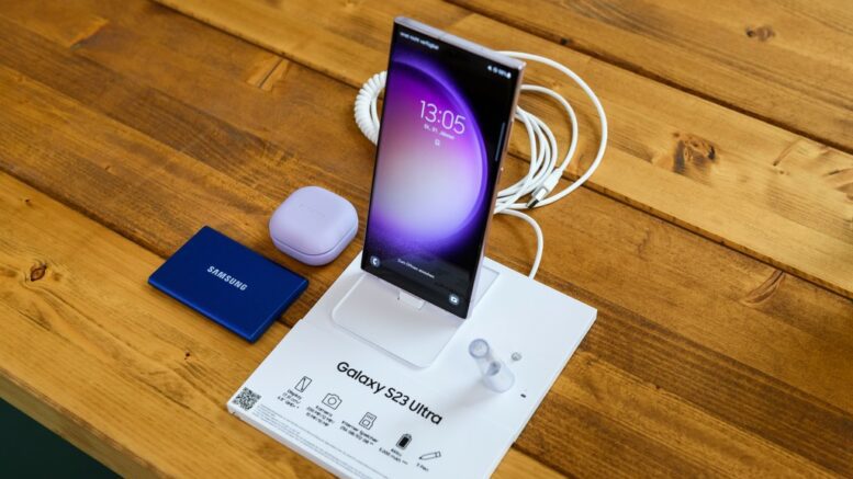 Samsung Galaxy S23 auf einem Holztisch mit Zubehör und Bedienungsanleitung