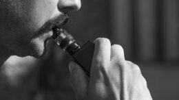 Ein Mann macht vaping mit einer E-Zigarette - schwarzweiß Foto